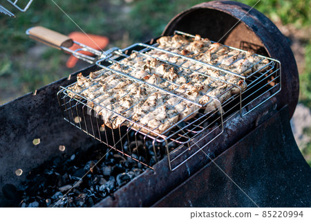 cooking raw meat in a grid on the barbeque grill 85220994