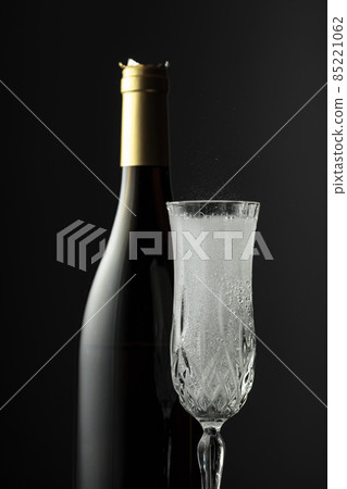 Bottle and glass of champagne on a black background. 85221062