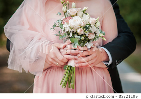 Groom and bride holding hands on the bouquet of flowers Groom and bride holding hands on the bouquet of flowers 85221199