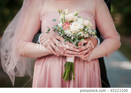 Groom and bride holding hands on the bouquet of flowers Groom and bride holding hands on the bouquet of flowers 85221200