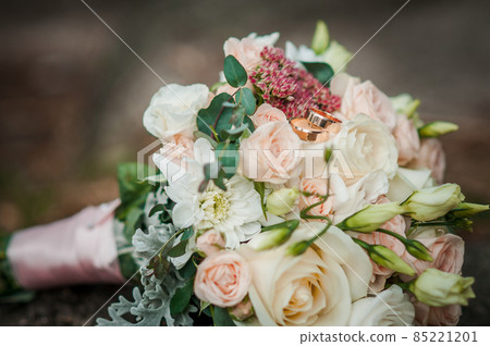 Gold wedding rings on the bouquet of flowers 85221201