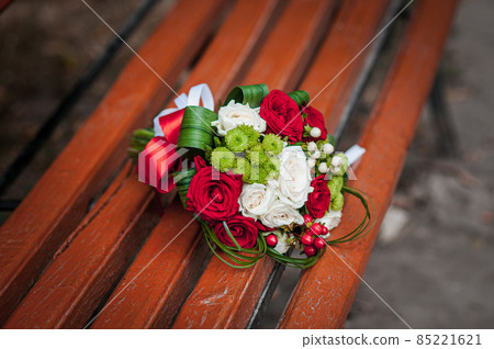 Red with white flower bouquet lies on a bench Red with white flower bouquet lies on a bench 85221621
