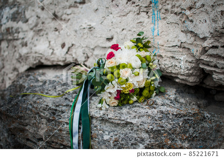 Colorfull bouquet of roses on the stone with pair of gold wedding rings Colorfull bouquet of roses on the stone with pair of gold wedding rings 85221671