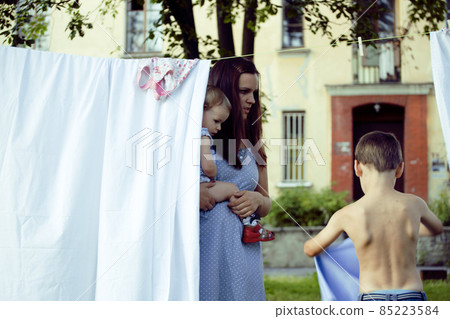 happy family making laundry outside, children helping 85223584