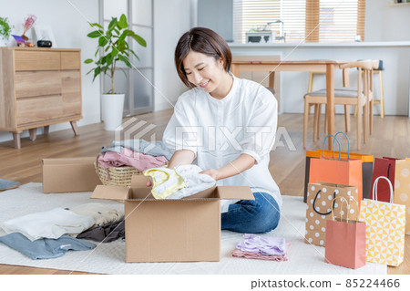 一個家庭主婦把客廳裡再也穿不著的童裝裝進硬紙板裡 85224466