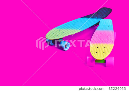 Two rainbow plastic Penny board skateboards on crimson background Two rainbow plastic Penny board skateboards on crimson background 85224933