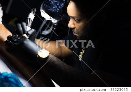The portrait of the tattoo artist concentrated on his work. Closeup. The portrait of the tattoo artist concentrated on his work. Closeup. 85225035