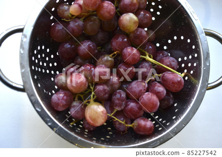 Freshly washed red grapes in a colander Freshly washed red grapes in a colander 85227542