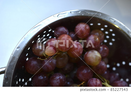 Freshly washed red grapes in a colander Freshly washed red grapes in a colander 85227543
