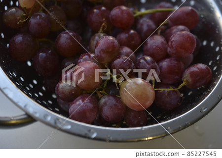 Freshly washed red grapes in a colander Freshly washed red grapes in a colander 85227545