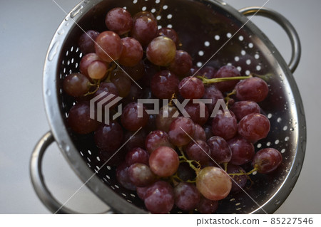Freshly washed red grapes in a colander 85227546
