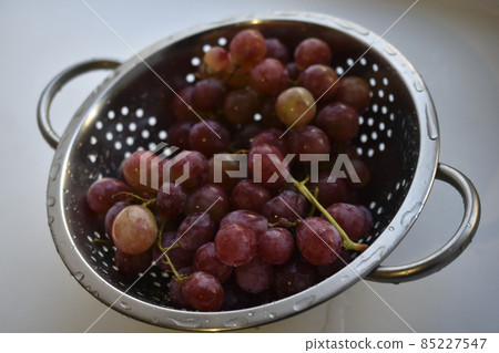Freshly washed red grapes in a colander 85227547