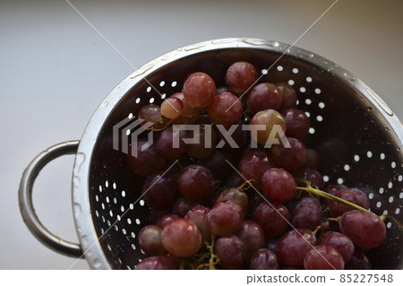 Freshly washed red grapes in a colander Freshly washed red grapes in a colander 85227548