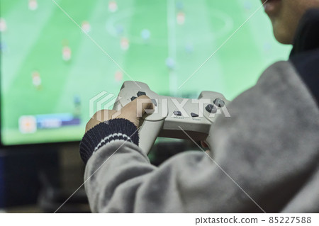 A little boy playing soccer on a gaming console. Cropped shot of a kid from behind, playing football game on wireless gamepad or joystick on his hands A little boy playing soccer on a gaming console. Cropped shot of a kid from behind, playing football game on wireless gamepad or joystick on his hands 85227588