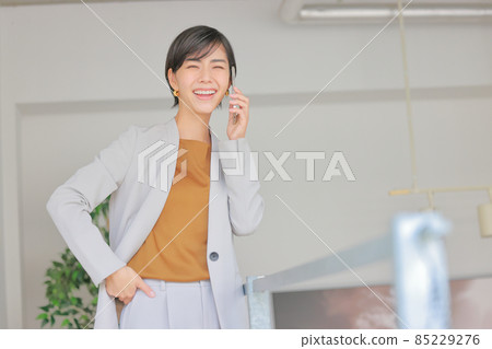 Business woman who puts her hand on her waist and makes a phone call 1 Business woman who puts her hand on her waist and makes a phone call 1 85229276