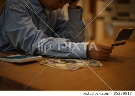 A woman worried while looking at her passbook A woman worried while looking at her passbook 85229817