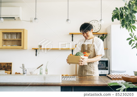 一個男人在廚房的紙板箱裡放著蔬菜 85230203