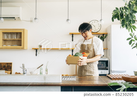 一個男人在廚房的紙板箱裡放著蔬菜 一個男人在廚房的紙板箱裡放著蔬菜 85230205