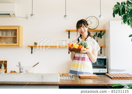 A woman holding a vegetable in the kitchen A woman holding a vegetable in the kitchen 85231135