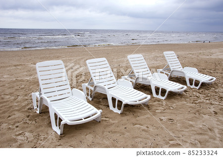 empty white chairs near sea on beach sand empty white chairs near sea on beach sand 85233324
