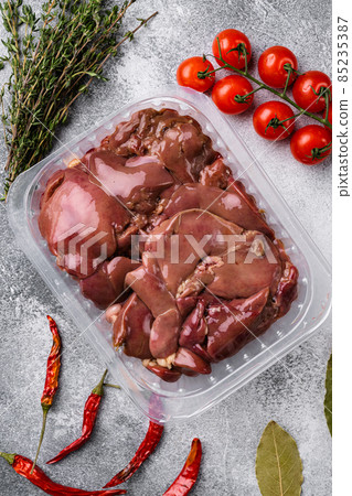 Poultry offal Chicken liver in a plastic container, on gray stone table background, top view flat lay Poultry offal Chicken liver in a plastic container, on gray stone table background, top view flat lay 85235387