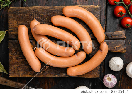 Boiled sausage, on old dark wooden table background, top view flat lay Boiled sausage, on old dark wooden table background, top view flat lay 85235435