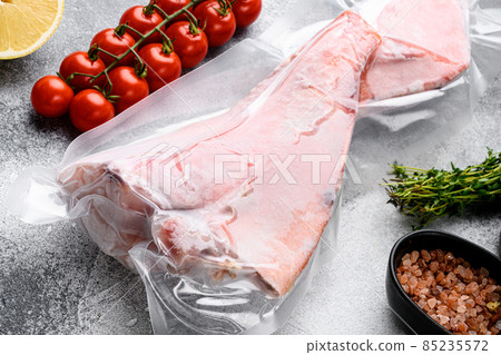 Orange roughy frozen pack fish meat, with herbs, on gray stone table background Orange roughy frozen pack fish meat, with herbs, on gray stone table background 85235572
