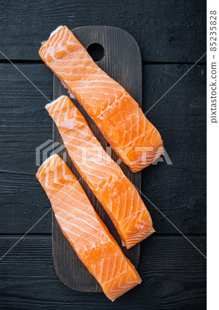 Raw salmon fillets, on black wooden table, top view Raw salmon fillets, on black wooden table, top view 85235828