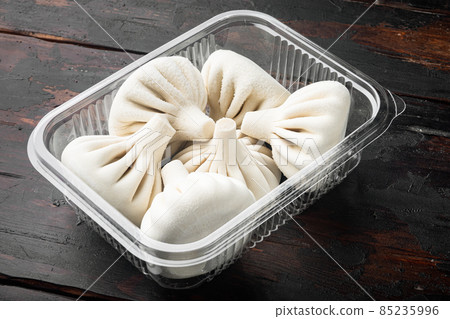 Khinkali Dumplings with beef and lamb meat, in plastic tray, on old dark wooden table background Khinkali Dumplings with beef and lamb meat, in plastic tray, on old dark wooden table background 85235996