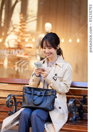 A woman looking at a smartphone on a bench 85238763