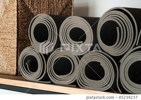 Gray yoga mats lying on a shelf, rolled up Gray yoga mats lying on a shelf, rolled up 85239237