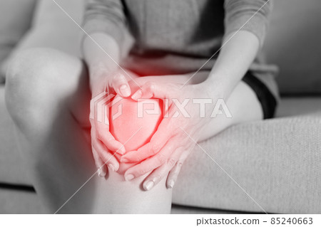 A woman suffering from feeling knee pain sitting sofa at home. hand massaging his painful knee. Health care and medical concept. A woman suffering from feeling knee pain sitting sofa at home. hand massaging his painful knee. Health care and medical concept. 85240663