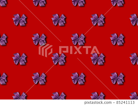 Purple bow for decorating gifts on a red background. Beautifully tied bow. Photo of a gift package with a seamless pattern. Purple bow for decorating gifts on a red background. Beautifully tied bow. Photo of a gift package with a seamless pattern. 85241113