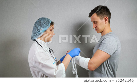 Brunette doctor examines broken forearm of young man Brunette doctor examines broken forearm of young man 85242146