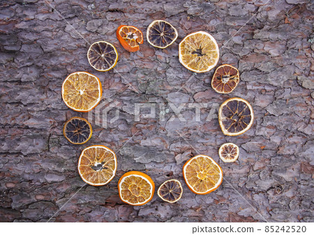 Decor of dried orange slices on tree bark rough texture. Decor of dried orange slices on tree bark rough texture. 85242520