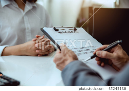 The boss signs the resignation letter to the female employee. 85245186
