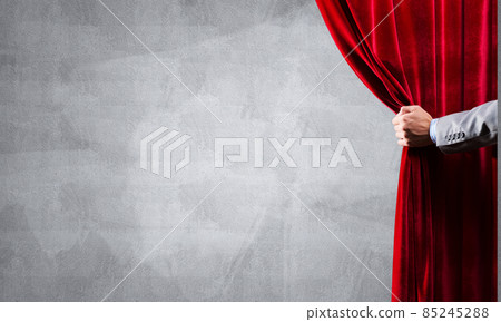 Concrete wall behind drapery curtain and hand opening it Concrete wall behind drapery curtain and hand opening it 85245288