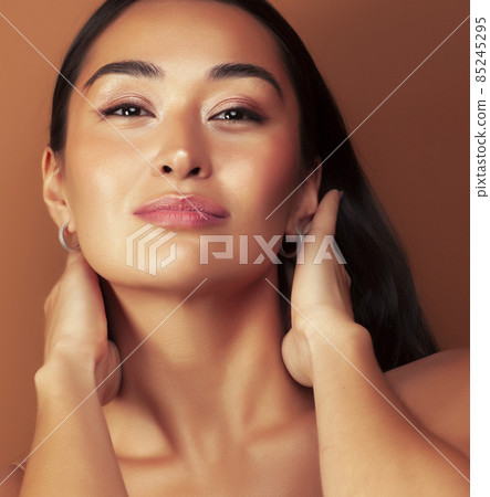 young pretty asian woman cheerful smiling posing on warm brown background, lifestyle people concept young pretty asian woman cheerful smiling posing on warm brown background, lifestyle people concept 85245295