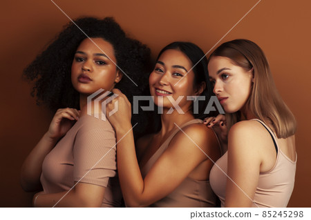 young pretty asian, caucasian, african woman posing cheerful together on brown background, lifestyle diverse nationality people concept young pretty asian, caucasian, african woman posing cheerful together on brown background, lifestyle diverse nationality people concept 85245298
