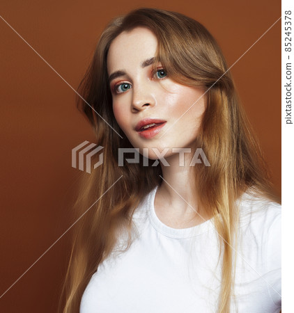 young pretty girl with blond hair posing cheerful on brown background, lifestyle people concept young pretty girl with blond hair posing cheerful on brown background, lifestyle people concept 85245378