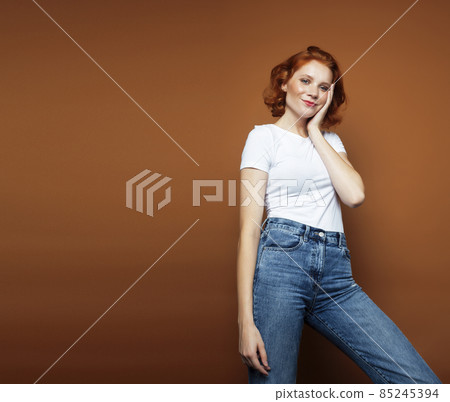 young pretty redhead girl posing cheerful on warm brown background, lifestyle people concept young pretty redhead girl posing cheerful on warm brown background, lifestyle people concept 85245394