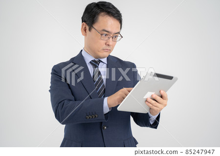 一個男人拿著平板電腦，認真地操作它——白色背景 85247947