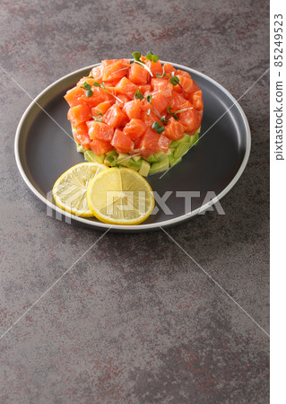 delicious avocado and salted salmon tartare, served with lemon, dark background delicious avocado and salted salmon tartare, served with lemon, dark background 85249523