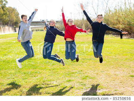 Happy teenagers jumping on the green lawn 85250656