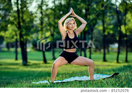 Mature woman in sportswear makes yoga exercises outdoors. Mature woman in sportswear makes yoga exercises outdoors. 85252076