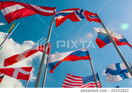 Bright flags of different countries against the blue sky and clouds 85252922