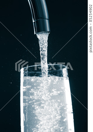 pouring a glass of water from mixer tap 85254902