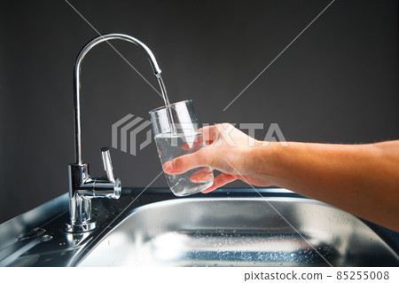 hand pouring a glass of water from filter tap 85255008