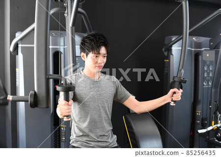 一個年輕人在健身房機器上做肌肉訓練（胸飛） 85256435