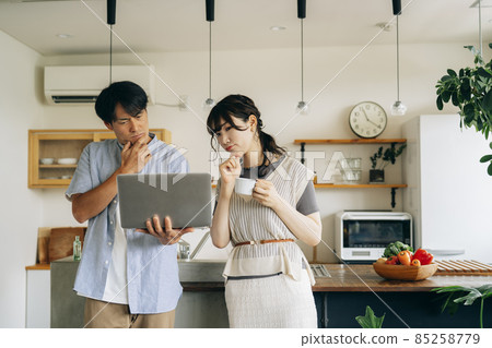 Men and women who use a computer in front of the kitchen (problem) Men and women who use a computer in front of the kitchen (problem) 85258779